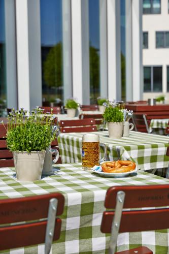 a table with a plate of food and a drink at H4 Hotel München Messe in Munich