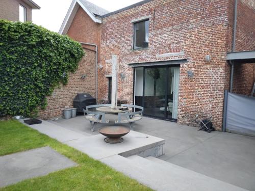 a patio with a table in front of a brick building at Gezellige moderne woning met zwemvijver in Halle
