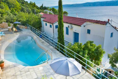 a house with a swimming pool and an umbrella at Apartments Miki in Donja Klada