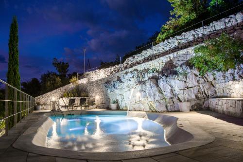 a swimming pool with a stone wall and anergynergynergynergynergyploadpload at Apartments Miki in Donja Klada
