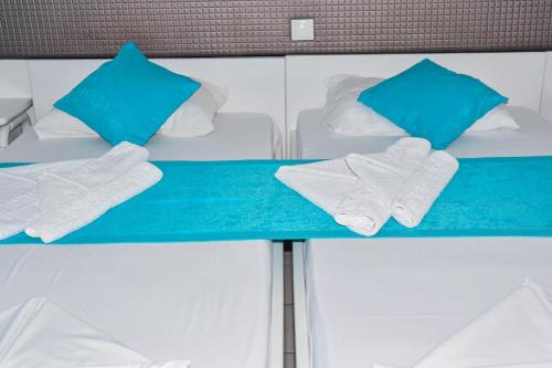 a bed with white towels and blue pillows at Blue Nest Hotel in Tigaki