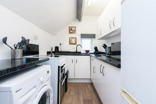 a kitchen with white cabinets and a washer and dryer at Large 1Bed Contractor & Pilot Flat - FREE Parking - FREE WiFI in Castle Donington