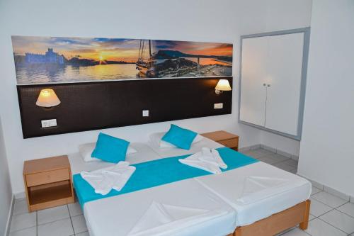 sypialnia z dużym białym łóżkiem z obrazem na ścianie w obiekcie Blue Nest Hotel w mieście Tigaki