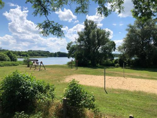 a park with a playground next to a lake at 'Glamping' Angelzelt am See mit Steg und Boot (Mecklenburger Seenplatte) in Blankensee