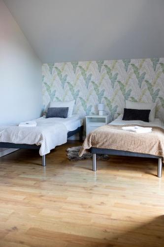 two beds in a room with wooden floors at Kalinowe Wzgórza in Charzykowy
