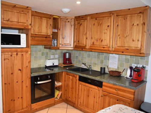 une cuisine avec des armoires en bois et un comptoir dans l'établissement Charmant 3P avec Terrasse & Jardin, Proche Commerces et Téléphérique - FR-1-464-26, à Pralognan-la-Vanoise