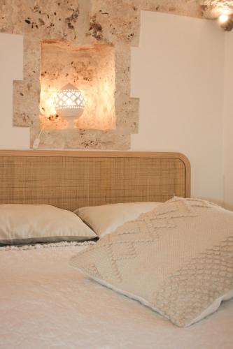 a bed with a headboard and a light on the wall at EnjoyTrulli - Countryside in Noci
