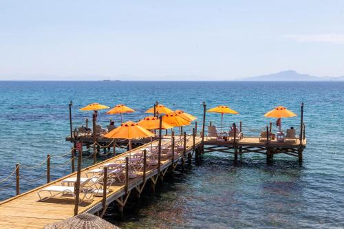 a pier with chairs and umbrellas on the water at Orcey Hotel in Datca