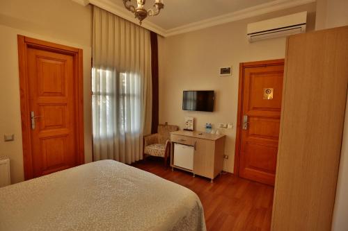 um quarto com uma cama, uma secretária e uma janela em Mimoza Butik Otel Buyukada em Buyukada