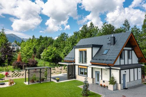 a house with a black roof and a yard at Śnieżka Exclusive Apartamenty in Kowary