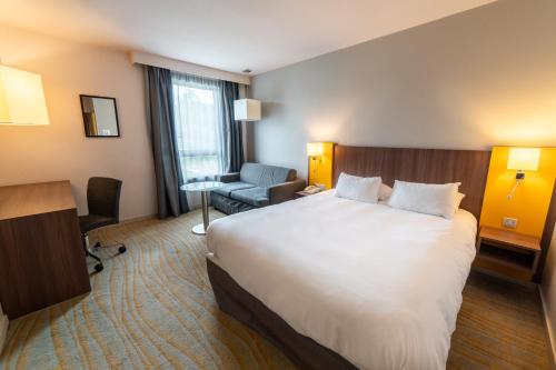 a hotel room with a large bed and a chair at Holiday Inn Lyon Vaise by IHG in Tassin-la-Demi-Lune