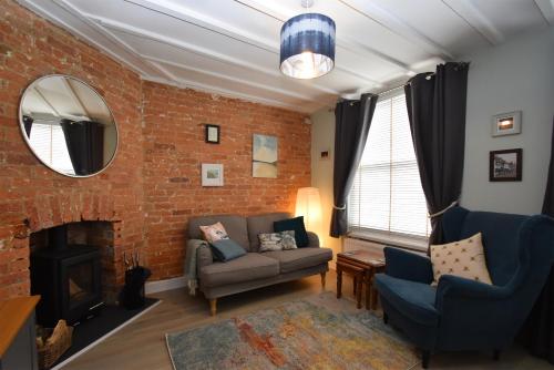 a living room with a couch and a brick wall at Honey Cottage in Rye