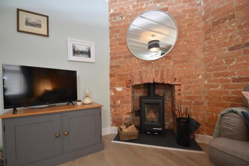 a living room with a fireplace and a flat screen tv at Honey Cottage in Rye