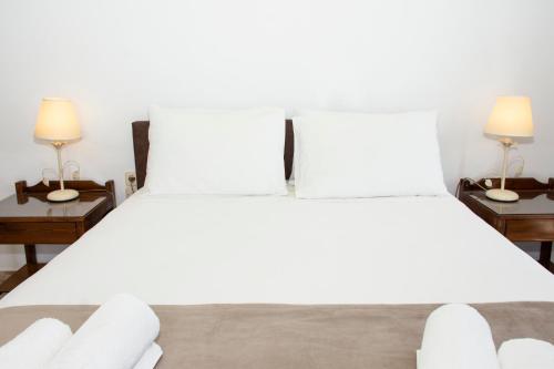 a bedroom with a large white bed with two lamps at Argo Rooms-Papadakis in Kissamos