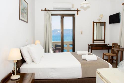 a bedroom with a large white bed with a view of the ocean at Argo Rooms-Papadakis in Kissamos