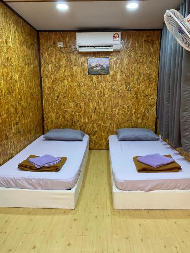 Igo Homestay - Standard Room في شاه عالم: سريرين في غرفة بها جدار
