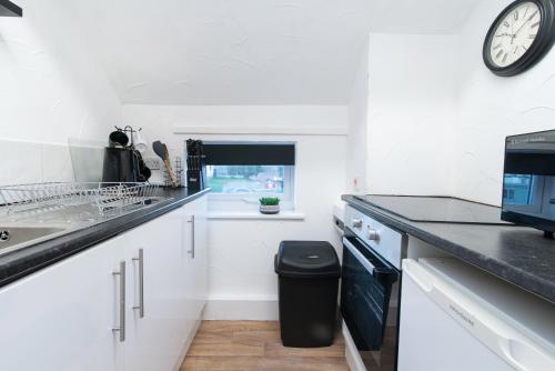 a kitchen with white cabinets and a clock on the wall at 1Bed Contractor & Pilot Flat - FREE Parking - FAST WiFi in Castle Donington