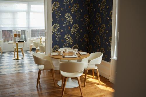 a dining room with a table and white chairs at Hôtel Échappée en Baie - Parking privé gratuit dont forfaits bornes électriques réservable in Saint-Valery-sur-Somme