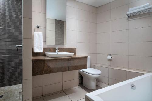 a bathroom with a sink and a toilet and a mirror at Premier Hotel East London ICC in East London