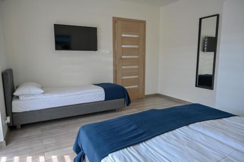 a bedroom with two beds and a flat screen tv at NORD HOUSE Apartamenty in Władysławowo
