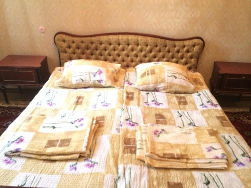 a bed with a quilt and pillows on it at Guest House Deda Lali in Kutaisi