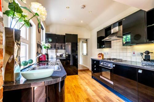 a large kitchen with black cabinets and a sink at Moatside Gate in York