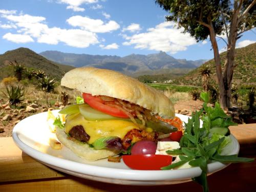 a sandwich on a plate on a table with a salad at Koedoeskloof Guesthouse in Ladismith