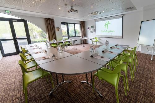 a meeting room with a large table and green chairs at Holiday Inn Lyon Vaise by IHG in Tassin-la-Demi-Lune