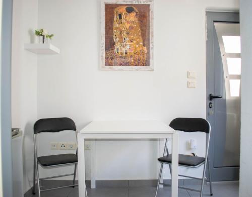 a white table with two chairs and a painting on the wall at Piraeus Urban Paradise L in Piraeus