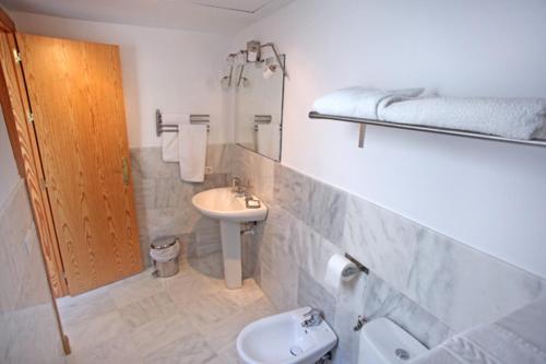 a white bathroom with a sink and a toilet at Sleepin Sevilla in Seville