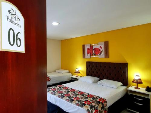 a hotel room with two beds and yellow walls at Hotel Três Palmeiras in Gravatá