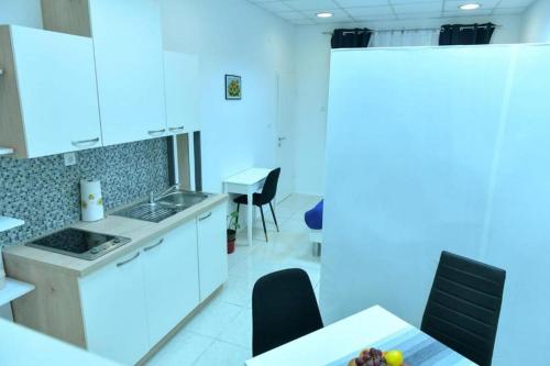 Studio Apartments Kamicak في سيني: مطبخ مع دواليب بيضاء وطاولة وكراسي