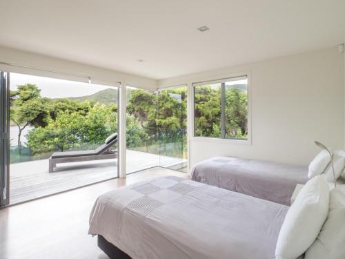 a bedroom with two beds and a large window at Oke Beach House - Rawhiti Luxury in Rawhiti
