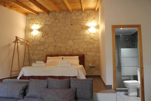 a bedroom with a bed with a stone wall at Citrus Garden in Nea Skioni