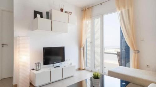 a white living room with a tv and a large window at ático Tarifa in Tarifa