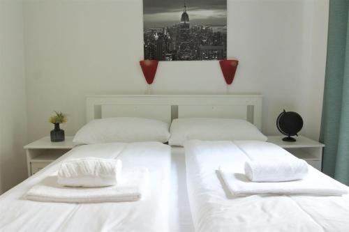 2 camas en una habitación con sábanas blancas y toallas en Hotel Pension ARPI, en Viena