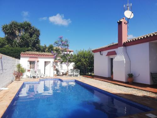 a villa with a swimming pool in front of a house at Girasoles in Chiclana de la Frontera