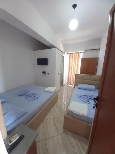 a bedroom with two beds and a table and a lamp at Bar Restorant Hotel Altini in Vlorë