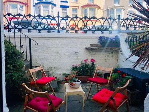 un grupo de sillas con cojines rojos en el patio en Walkden House, en Blackpool