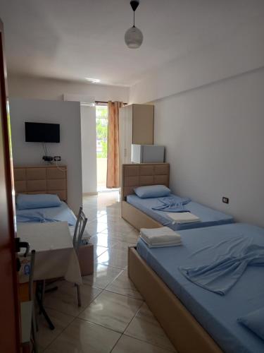 a bedroom with two beds and a table and a television at Bar Restorant Hotel Altini in Vlorë