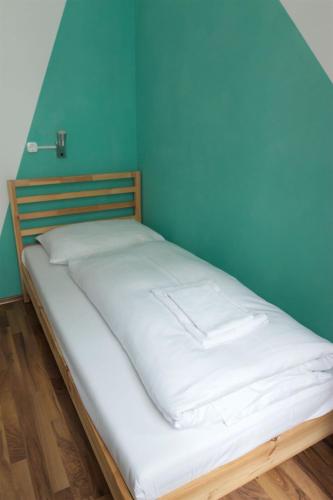 a white bed in a room with a blue wall at Hotel Pension ARPI in Vienna
