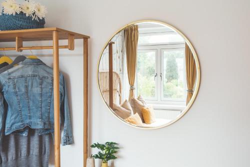 a round mirror hanging on a wall next to a window at Waves - Sea View Duplex Apartment, Stoke Fleming in Stoke Fleming