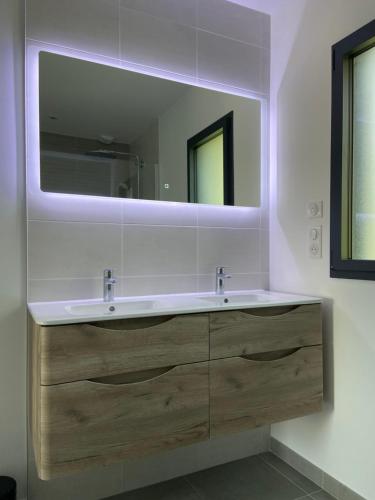 une salle de bain avec un lavabo et un grand miroir dans l'établissement Appartement avec terrasse et parking privé logement C, à Ploemeur