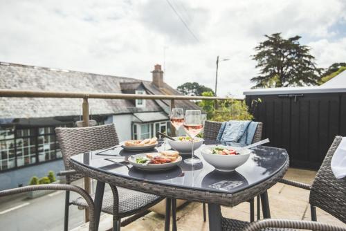 a table with bowls of food and glasses of wine at Waves - Duplex Apartment Stoke Fleming in Stoke Fleming