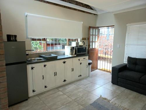 a kitchen with a refrigerator and a couch in a room at Lazy Days Apartments - Jeffreys Bay in Jeffreys Bay