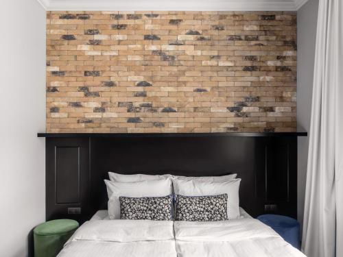 a bed with a black headboard and a brick wall at numa l Root Rooms & Apartments in Prague