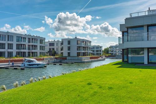 a river with buildings and a boat in the water at Grano Solmarina - Marina Residence SPA&Wellness in Wiślinka