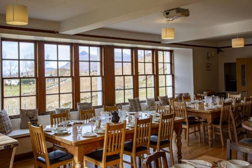 un comedor con mesas, sillas y ventanas en Inchnadamph Explorers Lodge, en Inchnadamph