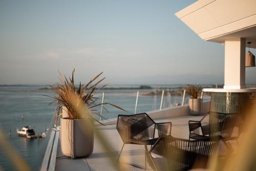 balcón con sillas y vistas al agua en Laguna Faro Suites - Adults Only & Free Beach, en Grado
