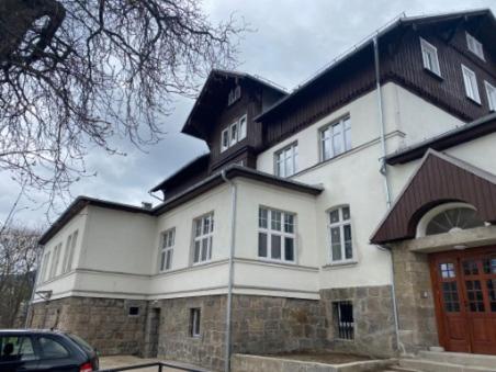 a large white building with a black roof at Apartament pod Świątynią Wang in Karpacz